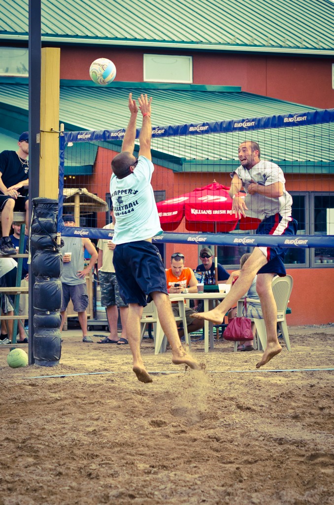 Two volleyball players jump at the net during a volleyball game at Trapper's Pizza Pub