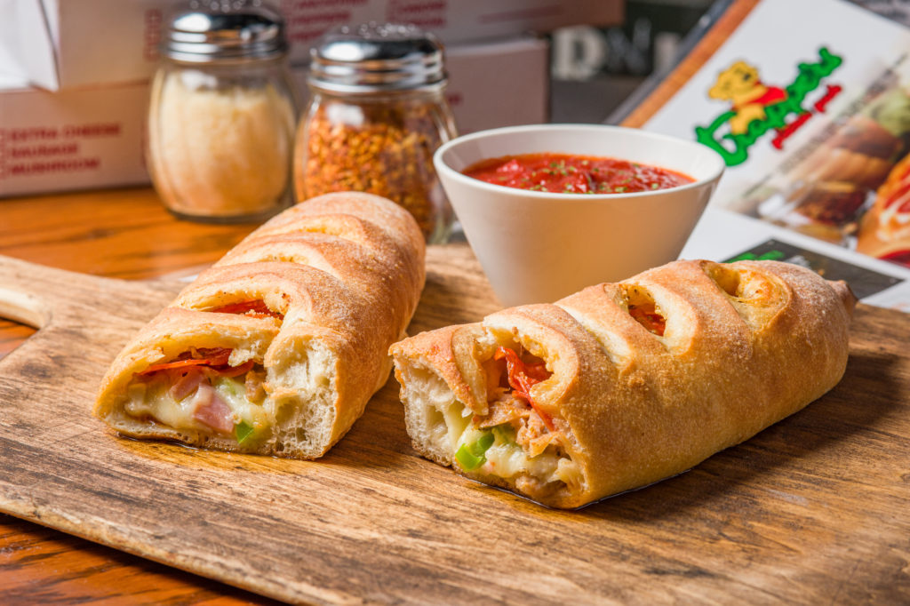 Fresh from the oven stromboli with a side of marinara sauce on a wooden pizza plank at Trapper's Pizza Pub