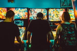 Teens play pinball at an arcade.